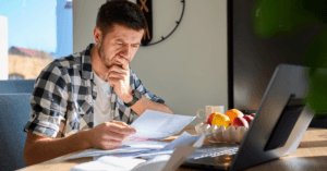 Man reviewing an international health insurance renewal at home after a premium increase.
